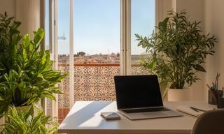 Sunlit Valencia apartment workspace with a laptop, plants, and tiled balcony